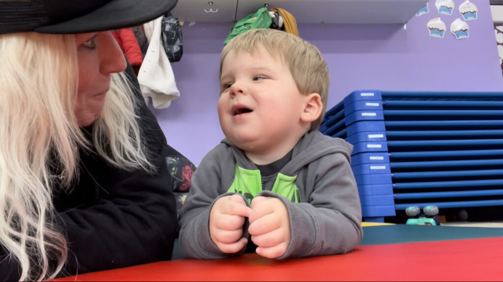 Woman and child lying on colorful mat, smiling.