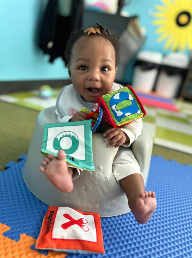 Baby playing with colorful toy blocks on mat.