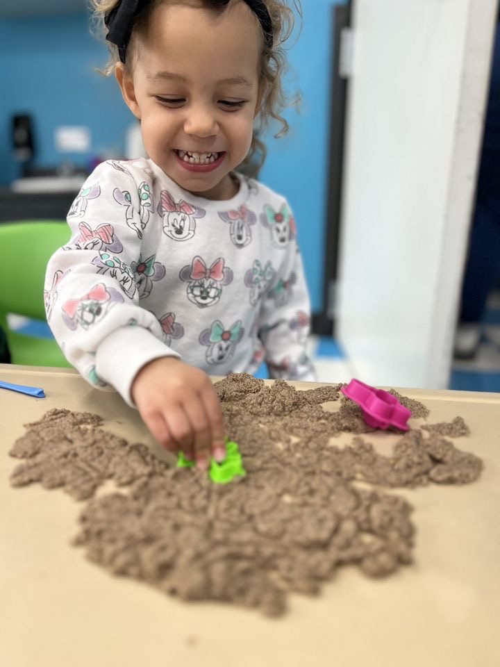 Child playing with sand using colorful molds