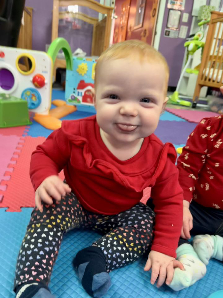 Smiling baby sitting on colorful play mat.
