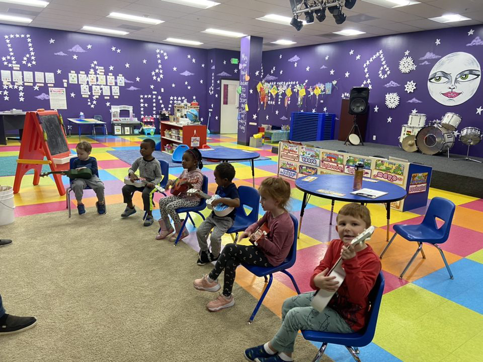 Children in colorful classroom playing instruments.
