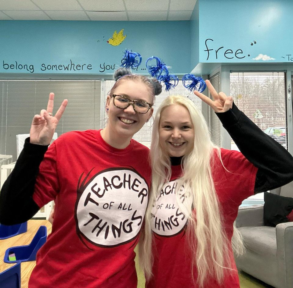 Two teachers smiling, wearing matching red shirts.