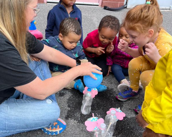 Children engaged in outdoor science experiment with balloons.