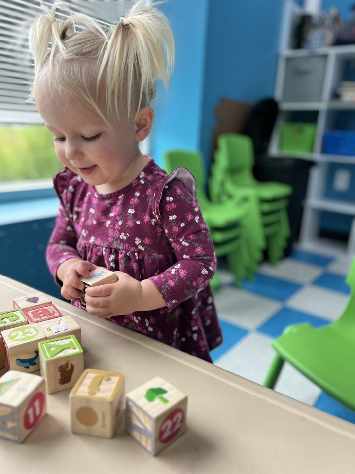 Child playing with colorful wooden blocks indoors.