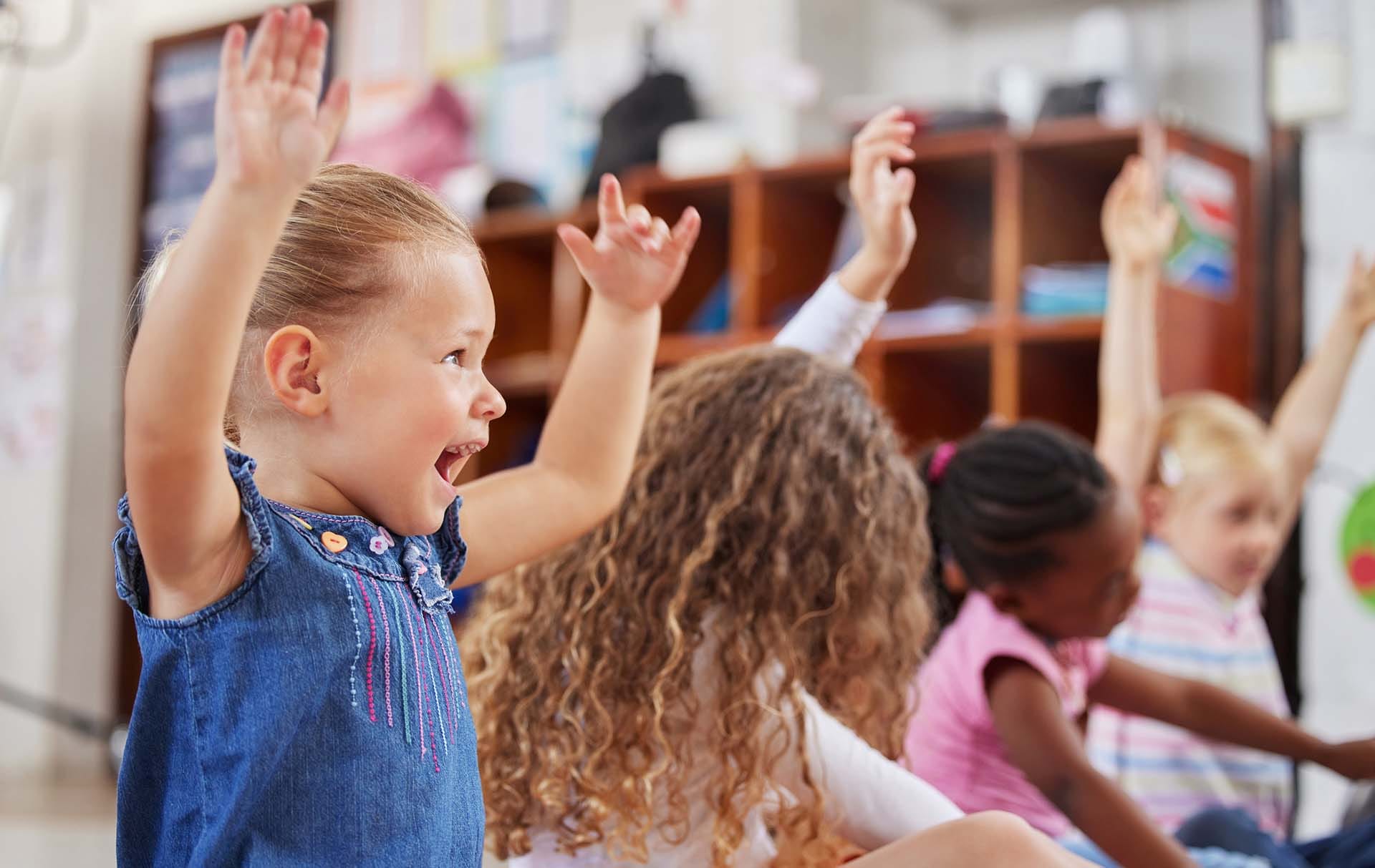 Children raising hands in day care in ownings mills, MD