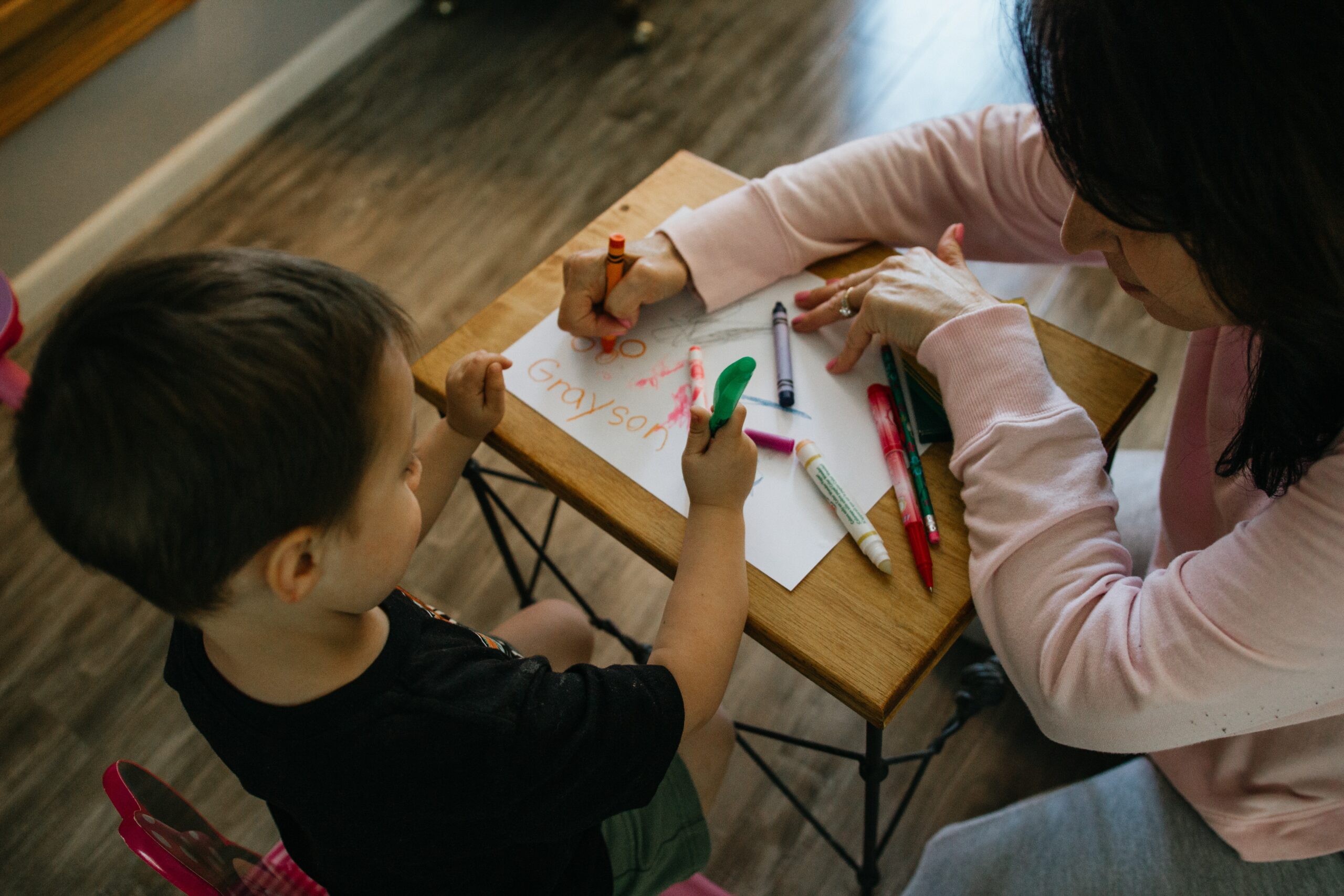 Child and adult coloring together at table.