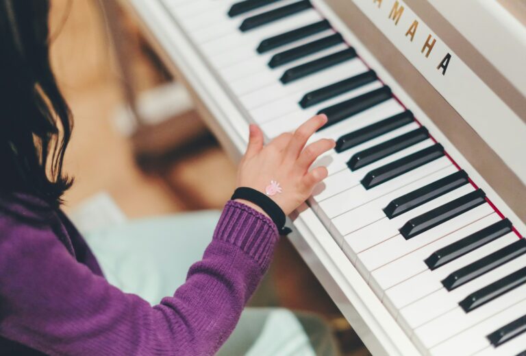 Child playing a white Yamaha piano.