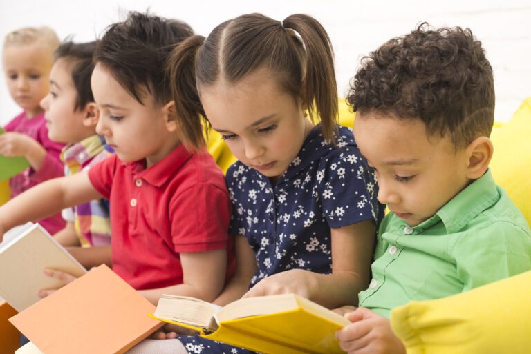Children reading books together on cushions.